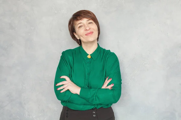 Lächelnde reife Frau mit grünem Hemd auf grauem Hintergrund — Stockfoto