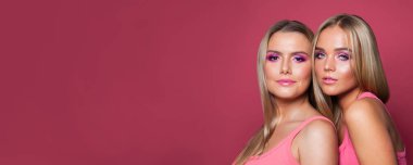 Makyajlı ve uzun sarı saçlı çekici genç kız kardeşler. 