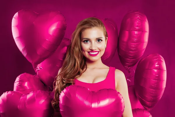 Young excited female model having fun and holding heart balloons — Stock Photo, Image