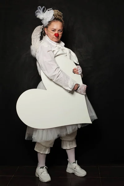 White clown woman with white empty heart banner on black background — Stock Photo, Image