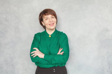Gri arka planda yeşil gömlekli mutlu akıllı iş kadını
