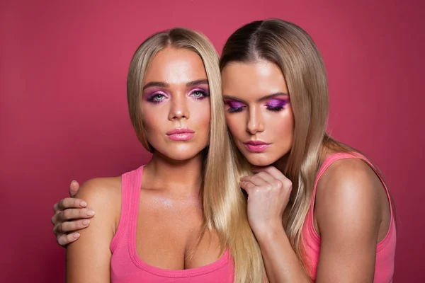 Mujeres atractivas con maquillaje de moda sobre fondo rosa — Foto de Stock
