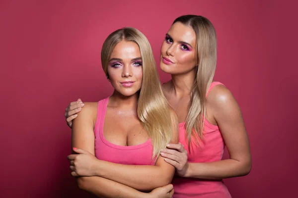 Dos modelos rubias chicas en camisa rosa sobre fondo rosa — Foto de Stock
