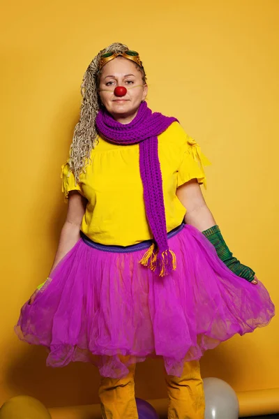 Mujer con traje de payaso colorido sobre fondo amarillo vivo — Foto de Stock