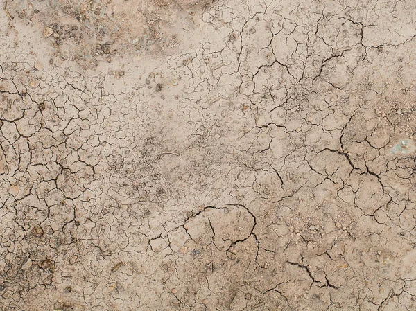 El suelo tiene grietas en la vista superior para el fondo o el diseño gráfico con el concepto de sequía y muerte —  Fotos de Stock