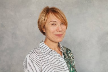 Gri arka planda neşeli olgun kadın