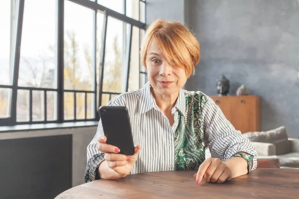 Шокированная взрослая женщина смотрит на телефон — стоковое фото