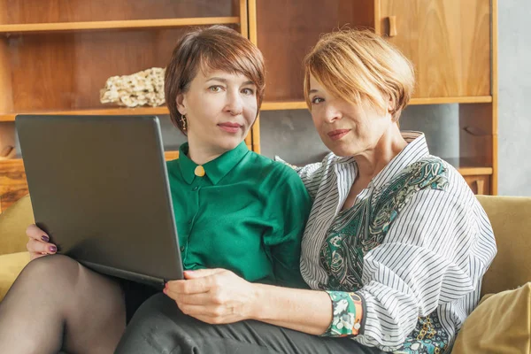 Привлекательные женщины среднего возраста с ноутбуком в помещении — стоковое фото