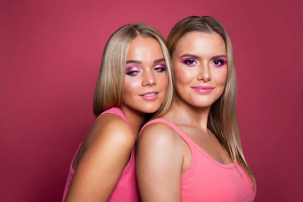 Zwei glücklich lächelnde Frauen auf rosa Hintergrund — Stockfoto