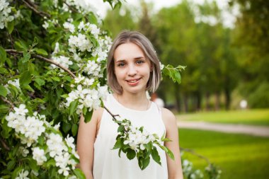 Bahar çiçeklerinin bahçesinde gülümseyen genç bir kadın