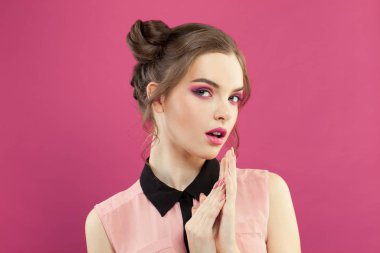 Parlak pembe arka planda canlı makyajlı güzel bir kadın.