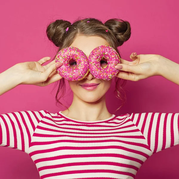 Çekici Bir Genç Kadın Pembe Arka Planda Iki Donut Gösteriyor — Stok fotoğraf