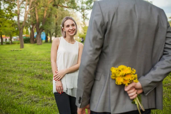 幸せな女の子は手に花を持つ若い男です ロマンチックな驚きと日付の概念 — ストック写真