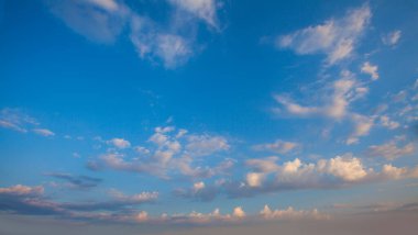 Mavi gökyüzü arka planda. Bulutları ve gökyüzünde turuncu güneşi olan güzel bir manzara.