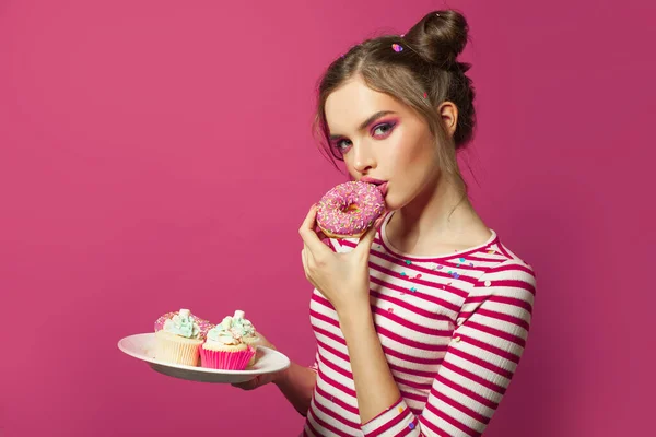 Ωραία Γυναίκα Τρώει Ντόνατ Και Κεκάκι Ροζ Φόντο — Φωτογραφία Αρχείου
