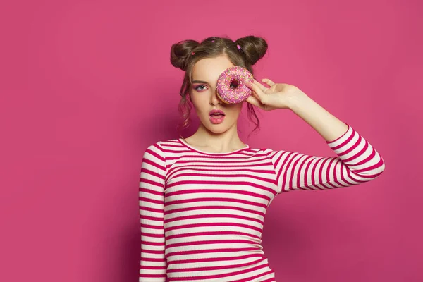 Sweet funny model woman with colorful donut on bright pink background