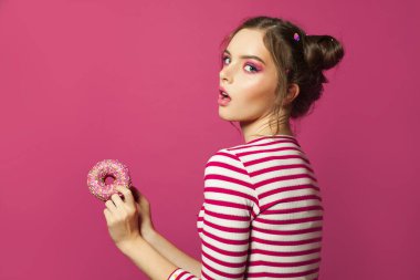 Renkli pembe arka planda donutu olan sürpriz kadın, diyet konsepti.
