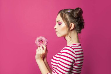 Canlı pembe arka planda donut tutan çekici kadın, diyet konsepti.