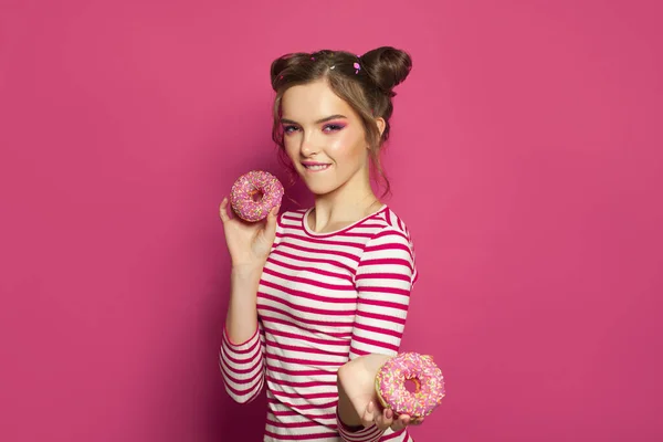 面白い女の子とドーナツ上のカラフルなピンクの背景 食事のコンセプト — ストック写真