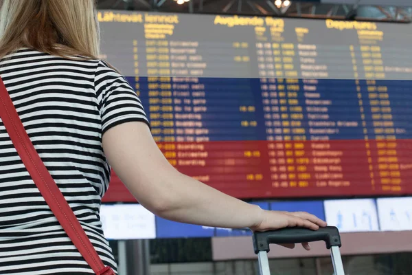 Woman looks at the scoreboard at the airport. Select a country Russia for travel or migration.