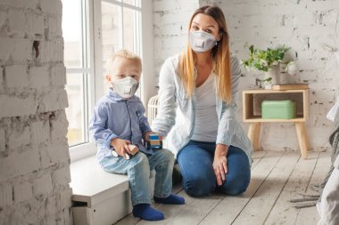 Evde tıbbi maskeli bir aile var. Kadın ve küçük çocuk