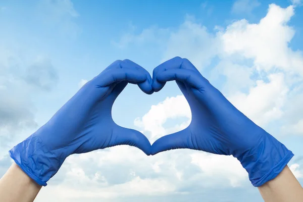 Doctor hands showing heart against sky clouds