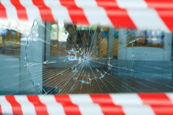 Сломанная витрина с предупреждающей лентой. Разбитое окно
