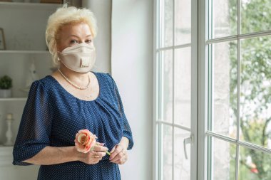Koruyucu maskeli yaşlı kadın evde, 70 yaşında.