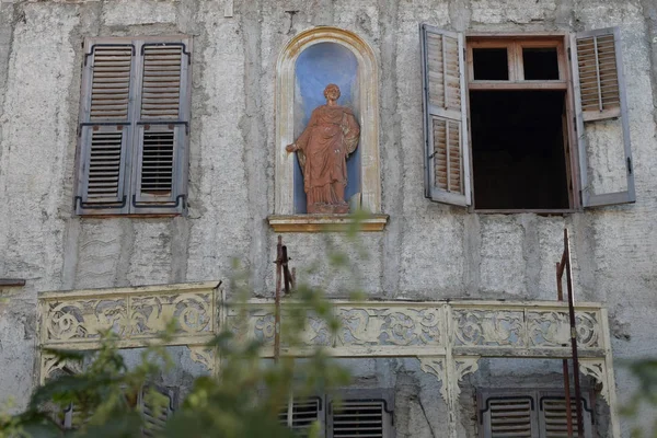 Building facade with weathered statue — Stock Photo, Image