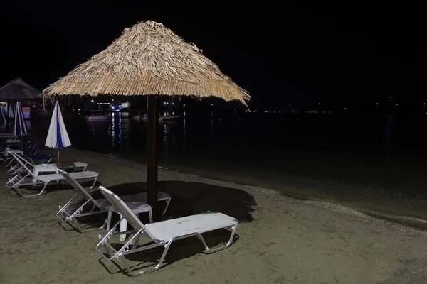 Beach chairs and umbrellas at night — Stock Photo, Image