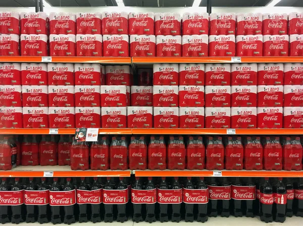 Cans and bottles of coca-cola in supermarket aisle — Stock Photo, Image
