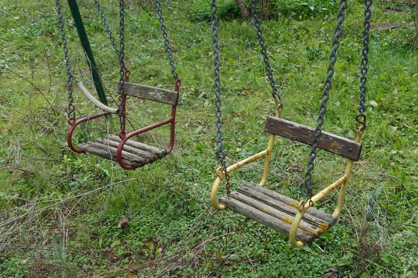 Baloiços de madeira em playground desaproveitado — Fotografia de Stock