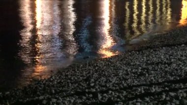 Neon lights reflected on sea water. Beach at night.
