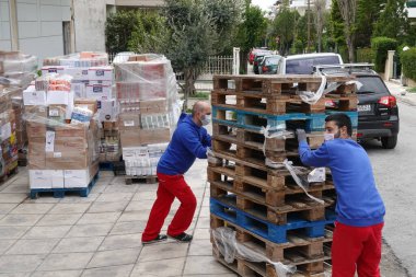 Atina, Yunanistan - 16 Mart 2020: Korunaklı yüz maskesi takan süpermarket çalışanları Coronavirus covid-19 salgını sırasında paketli yiyeceklerle paletleri boşalttılar.