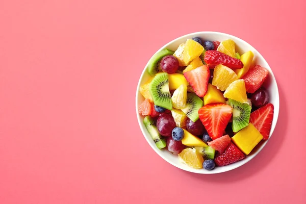 Čerstvý ovocný salát na růžovém pozadí — Stock fotografie