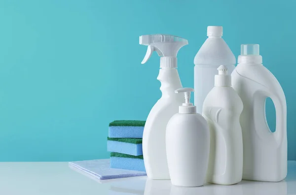 異なる洗浄製品の白いボトルのセットとテキストのための空のスペースと青の背景にスポンジ — ストック写真