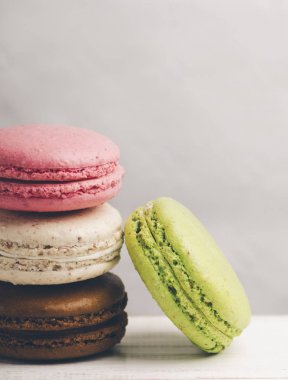 Retro pastel renkli macaroons antika arka plan üzerinde kazık. Ev yapımı Fransız macaron tatlı şeker ile farklı tatlar: çikolata, çilek, vanilya, Antep fıstığı.