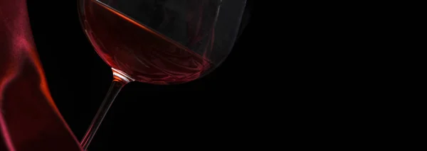 Szklanka czerwonego wina na czerwonym jedwabiu na czarnym tle. Kwas winowy — Zdjęcie stockowe