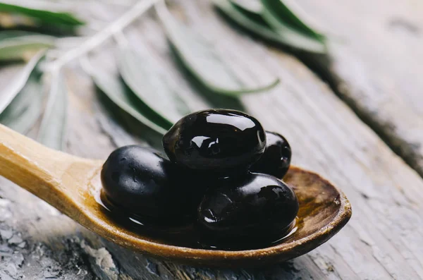 Närbild av färsk svart oliv i olja på rustika trä bord. Organi — Stockfoto