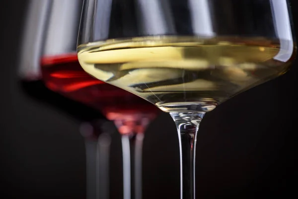 Trzy kieliszki czerwonego, różowego i białego wina na czarnym tle. W — Zdjęcie stockowe