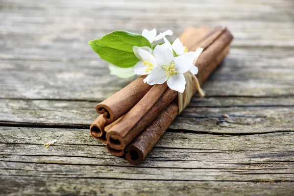 Cinnamon sticks and jasmine flower on vintage wooden table. Clos — Stock Photo, Image