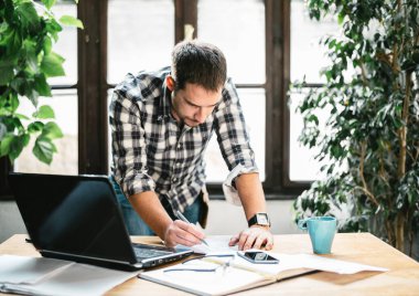 Genç adam havalı ofisinde uzaktan kumandalı çalışıyor. Çevrimiçi iş ve yaratıcı dijital proje için modern çalışma alanı stüdyosu. İnternet mesleği, çevrimiçi alışveriş, eğitim ve öğrenim kavramı.