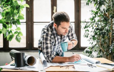 Ev ofisinden çalışan bir mimar serbest yenileme projesi üzerinde çalışıyor. Genç serbest yazar uzak iş için yaratıcı tasarım fikrini çiziyor. Serin çalışma alanında hippi bir adam.
