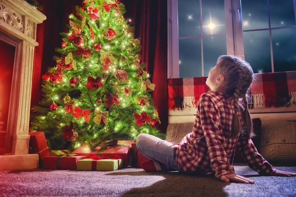 Meisje kijkend van de decoraties de kerstboom. — Stockfoto