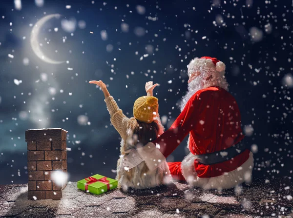 Menina e Papai Noel sentado no telhado — Fotografia de Stock