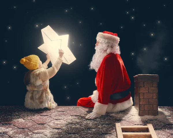 Дівчина і Санта-Клауса, сидячи на даху — стокове фото