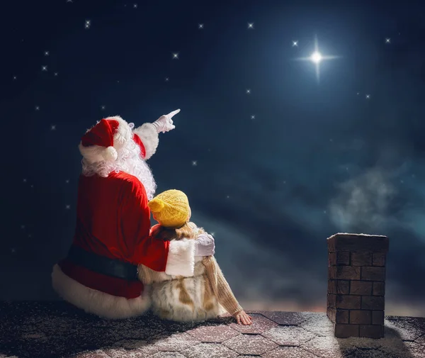 Menina e Papai Noel sentado no telhado — Fotografia de Stock