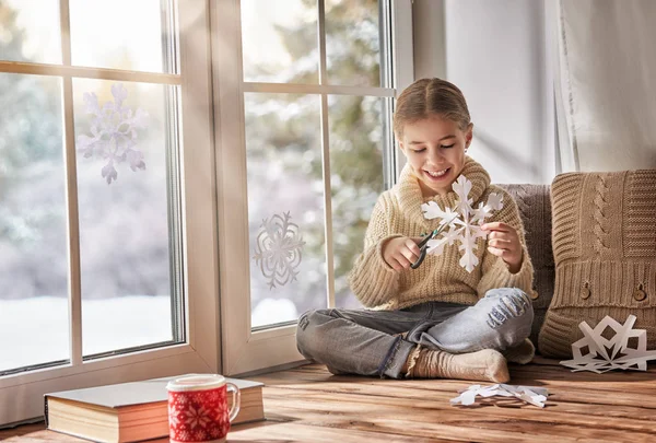 Niño hace copos de nieve de papel — Foto de Stock