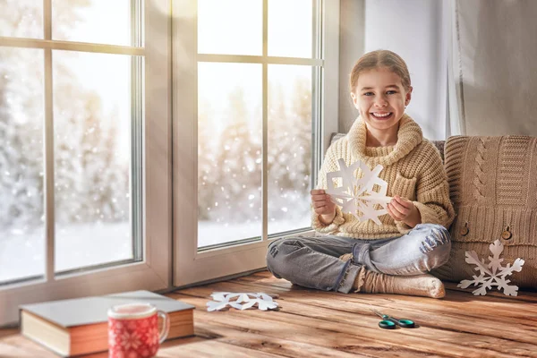 Criança faz flocos de neve de papel — Fotografia de Stock