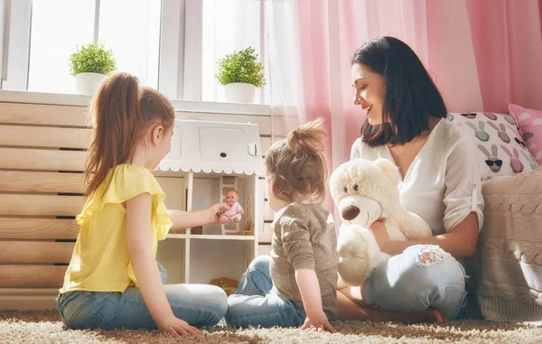 Mãe e filhas brincam com casa de boneca — Fotografia de Stock